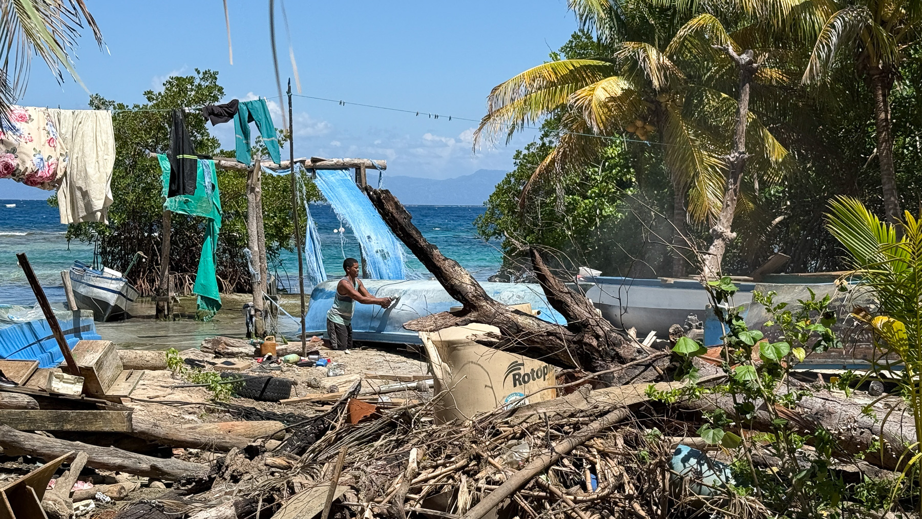 Ein Garifuna arbeitet im Dorf East End auf der Cayo Mayor an einem Boot - mitten im Durcheinander, das wie ein Sperrmüll-Haufen erscheint.