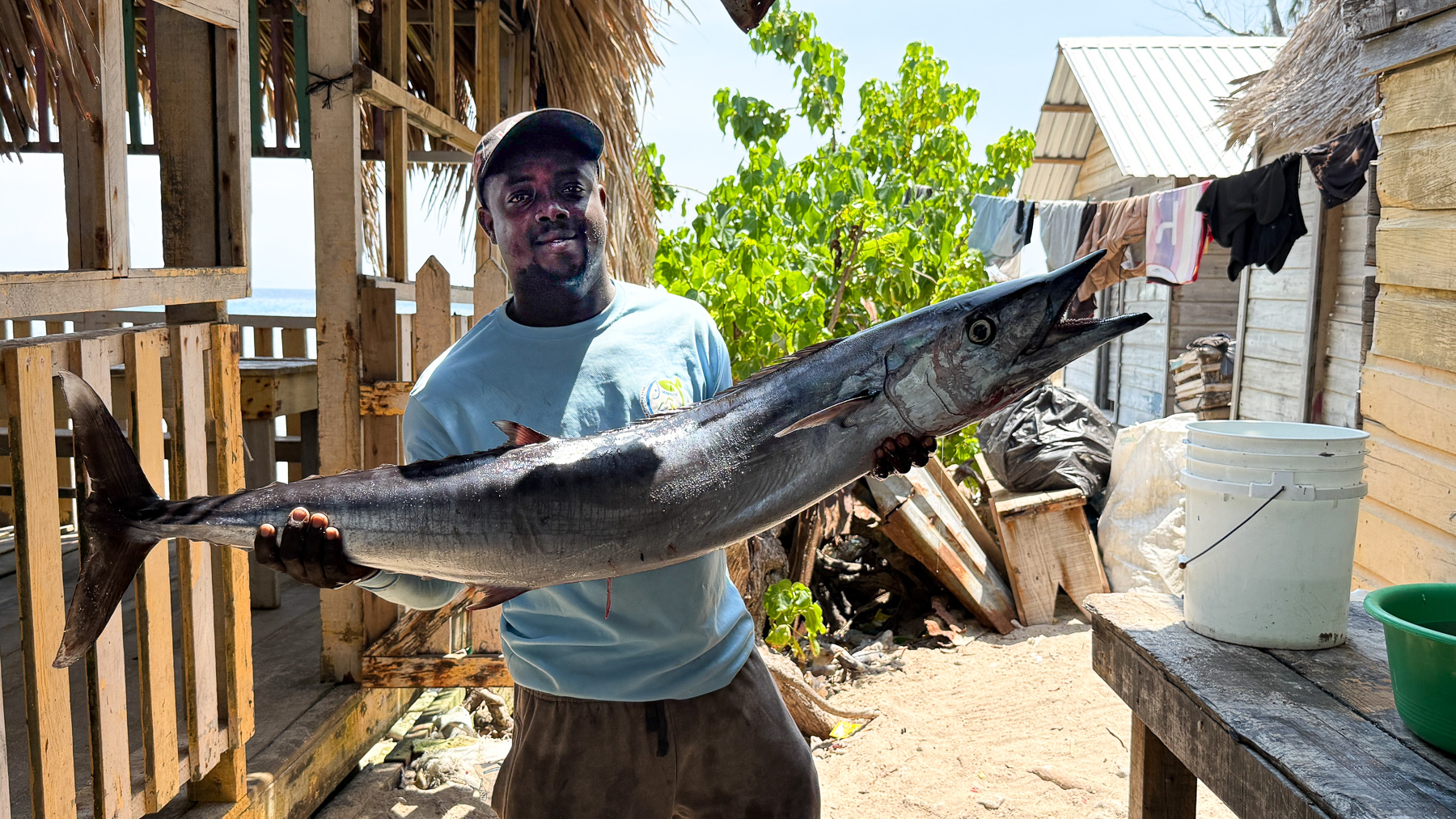 Ein Fischer in Chachahuate praesentiert seinen tollen Fang: ein Riesenbarrakuda, aus dem Meer gezogen auf den Cayos Cochinos, Honduras
